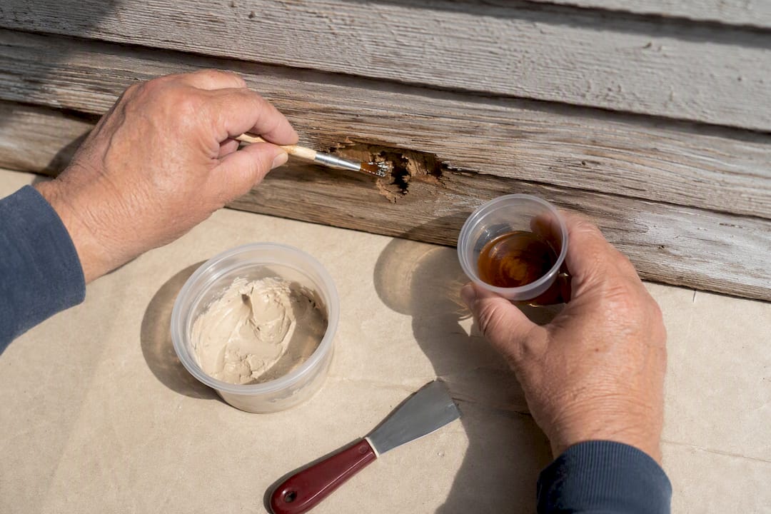 Applying epoxy filler to rotten siding