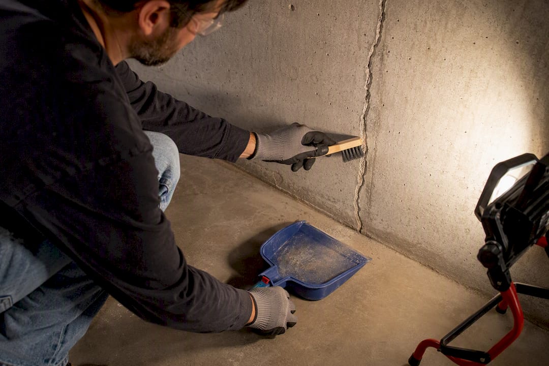 Hands cleaning concrete crack before injection